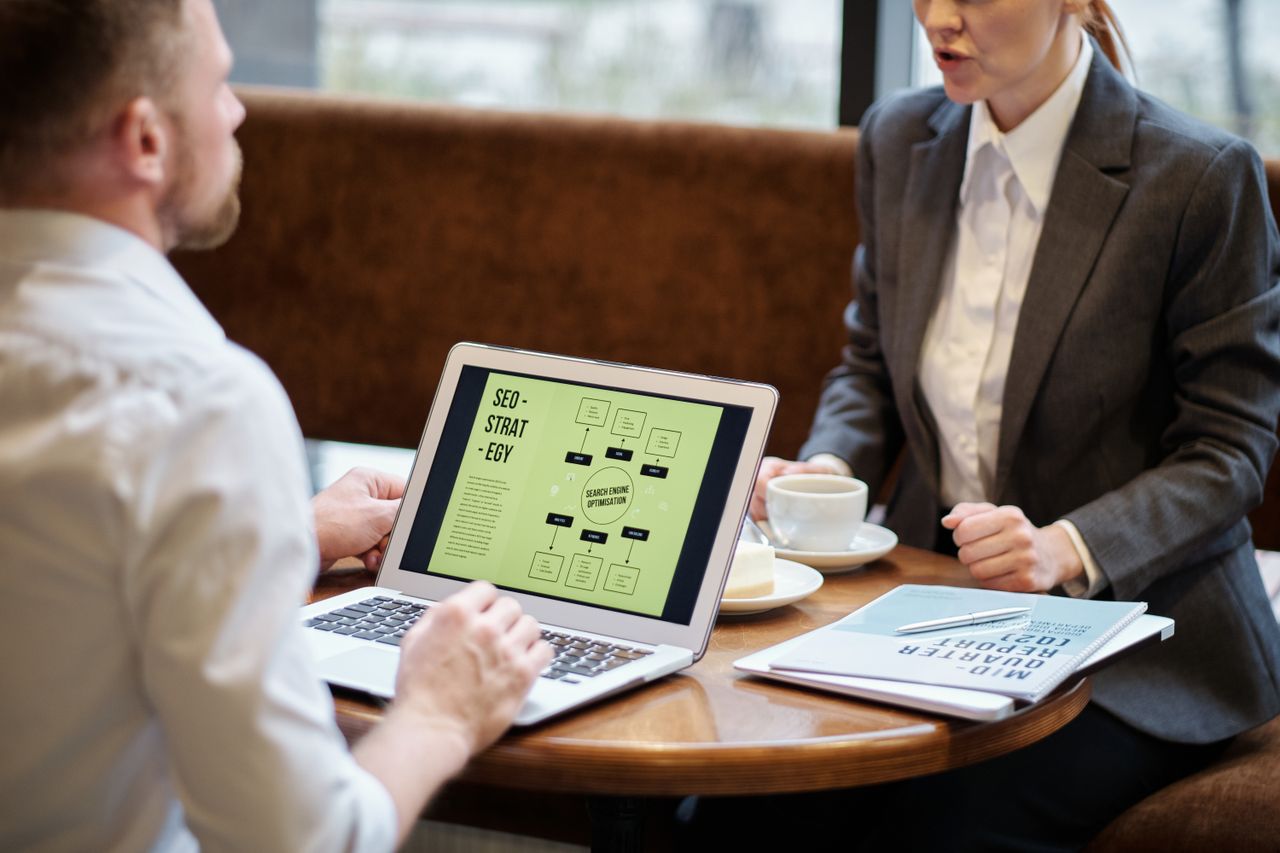 gallery-01 A man and woman engaged in a business meeting discussing SEO strategy in a cozy cafe setting.
