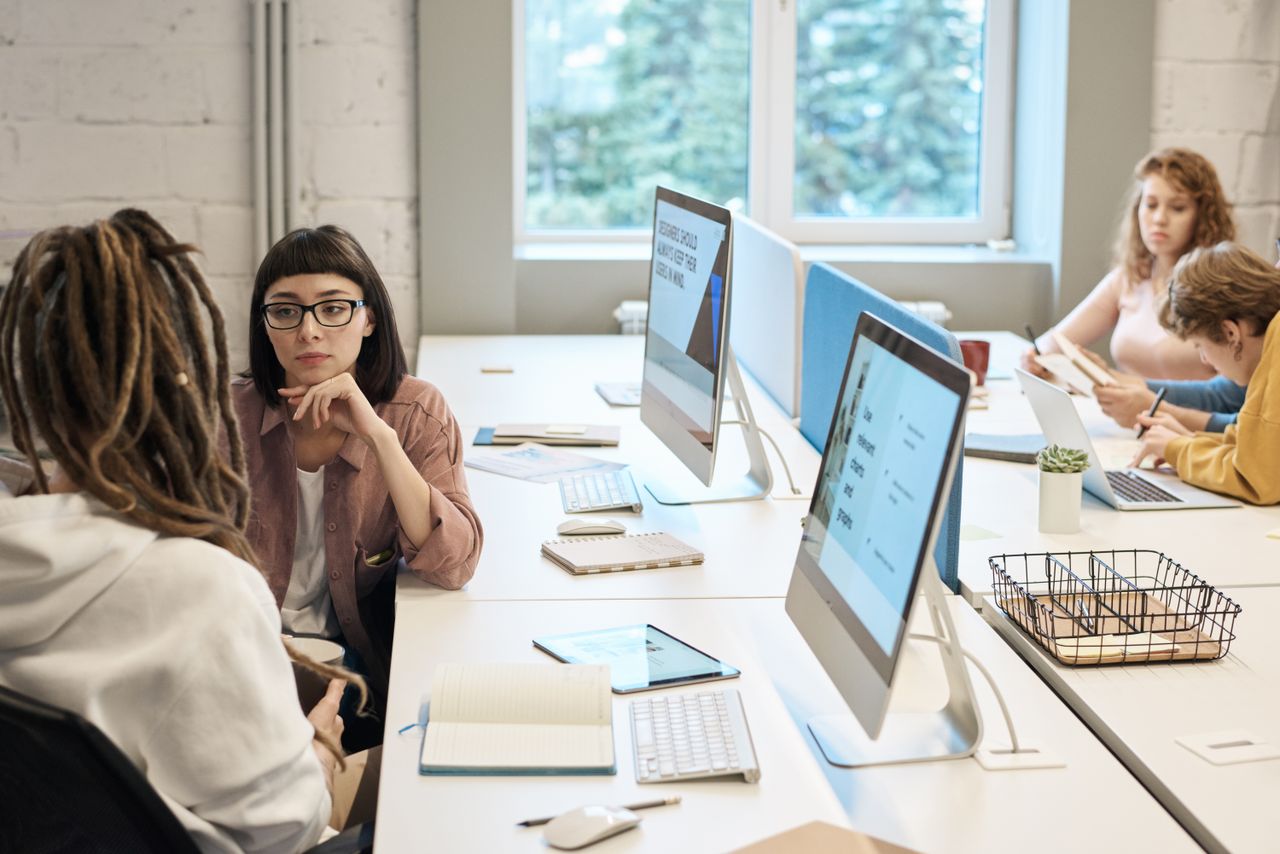 home-img Diverse group of women working together in a modern office setting, fostering teamwork and creativity.